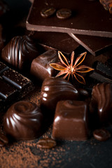 Assortment of dark, white and milk chocolate stack, chips. Chocolate and coffee beans on rustic wooden sacking background. Spices, cinnamon. Selective macro focus. Chocolates background. Sweets