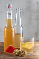 Two bottles and glass of kombucha drink on a wooden table with energy balls. Vertical orientation