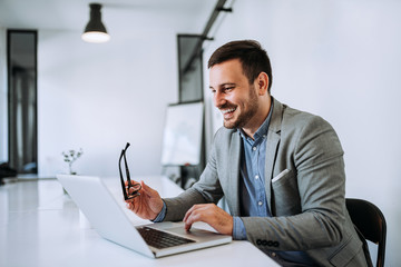 Happy entrepreneur reading good news on laptop.