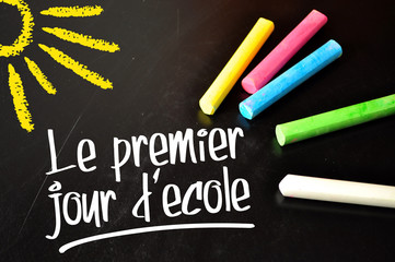 Chalkboard with coloured chalkb and the french words for frist schoolday - le premier jour decole