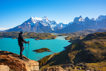 Hiker at mirador condor enjoying amazing view of Los Cuernos rocks and Lake Pehoe in Torres del Paine national park, Patagonia, Chile
