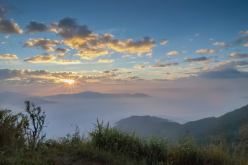 Fototapeta na wymiar Mountain view misty morning of top hills around with sea of mist with cloudy sky background, sunrise at Pha Tang, Chiang Rai, northern of Thailand.