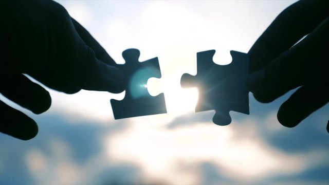 teamwork business finance concept. male hands connect two puzzles silhouette against the sunset. symbol teamwork of lifestyle association and connection. strategy business