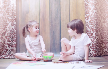 Naklejka premium Little children paint on a large sheet of paper