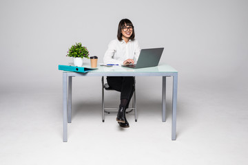 Concentrated young beautiful businesswoman working on laptop in modern office