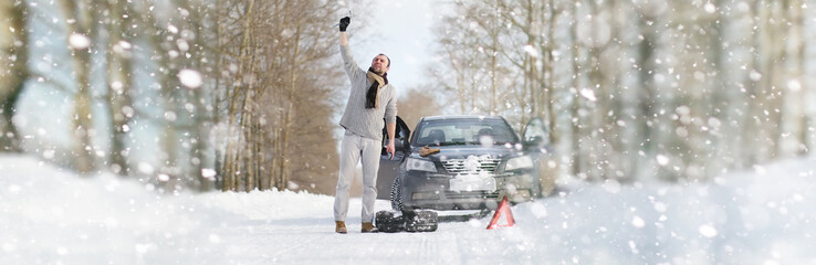 A man near a broken car on a winter day