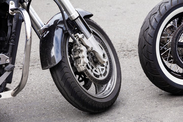Close-up of the front wheel of a motorcycle and brake disc. Chrome fork and black motorbike wing
