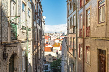 Fototapeta premium Narrow walkways along house facades and urban canyons with views of the city of Lisbon.
