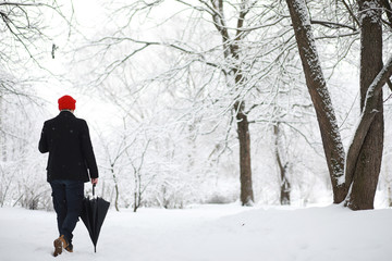 A man on a walk in the park. Young man with in the winter snowfall.