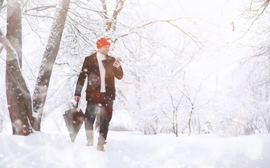 Fototapeta na wymiar A man on a walk in the park. Young man with in the winter snowfall.