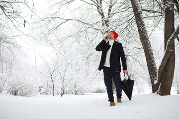 A man on a walk in the park. Young man with in the winter snowfall.