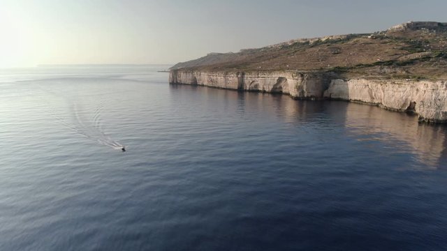 Wide Aerial Shot following a boat by Dingli Cliffs