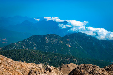 A several clouds clambering the top of mountains