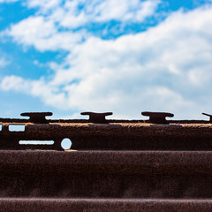Metallic rusty fence with a blue sky.