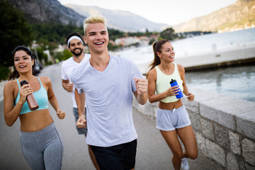 Happy fit people running and jogging together in summer sunny nature