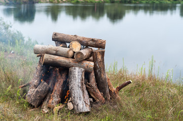Warming stones at the stake for a sauna in nature. Bonfire of large logs on the banks of the river.