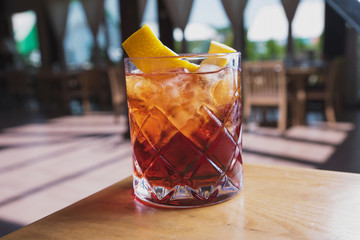 cocktail with soda, whiskey and orange zest on the background of a summer cafe on a wooden table