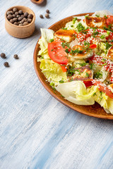 Close up view on green salad with tomato, halumi cheese, lettuce. Salad bowl with copy space. Blue background. Healthy food concpet. Healthy balanced appetizer plate