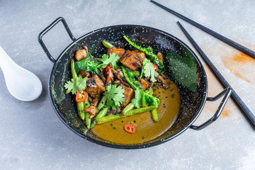 Top view Green curry with Tofu, parsley, asparagus in black bowl. Pan-asian food. Thai style vegetarian food. Balanced and healthy food for vegan. Flat lay food on grey stone background