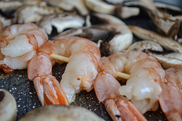 Macro close up of giant aromatic prawn tails spiced with natural herbs and grilled on wood skewer.