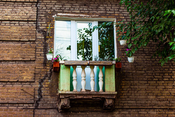 Fototapeta na wymiar Old vintage concrete balcony of a brick building decorated with flowers.