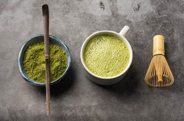 Japanese matcha green tea powder, a healthy natural product, antioxidant. Bamboo spoon and whisk. Gray background, close-up, top view.