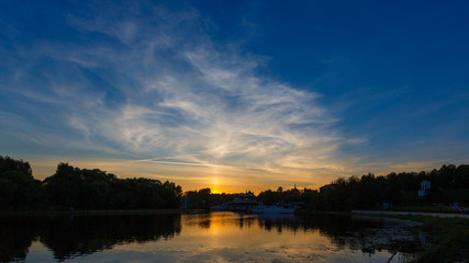 Fototapeta na wymiar Panorama of the evening sky with clouds in Yaroslavl. The setting sun is reflected in the water of the Kotorosl River.