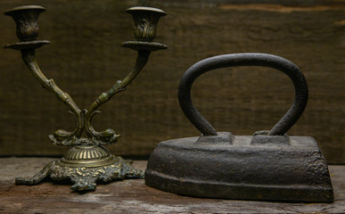 Vintage iron and candlestick with a metal texture.Both items stand on old and rotten shelf
