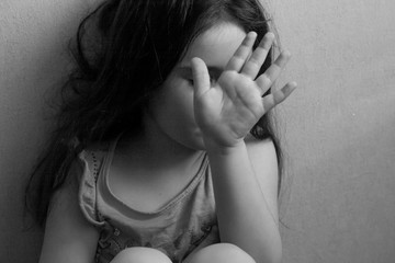 black and white portrait of emotional angry little girl closing her face with her hand who doesn't...
