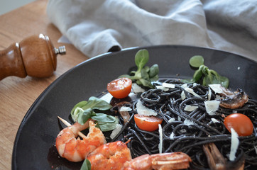 Mediterranean pasta. Spaghetti with cuttlefish ink and clams. On a rustic background.