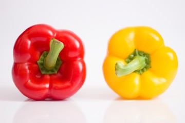 red and yellow paprika on white reflective background. vivid colours and lots of highlights.