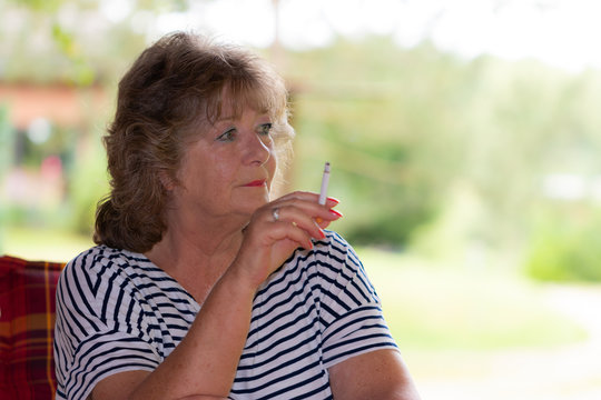 blonde gepflegte sympathische Frau raucht eine Zigarette.