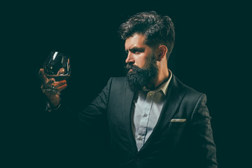 Man with beard holds glass brandy. Degustation and tasting. Sipping whiskey.