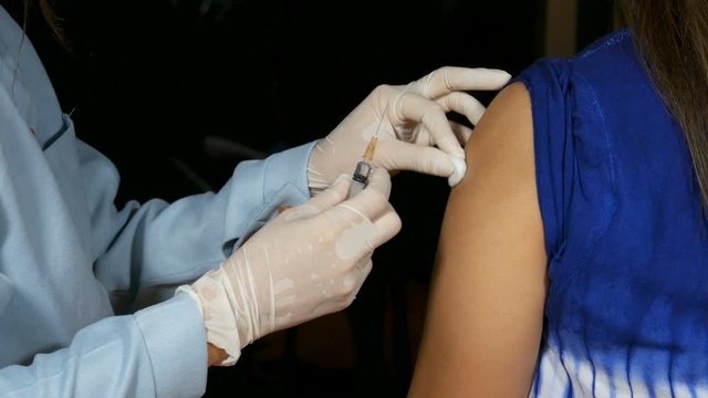 Doctor injecting flu vaccine to patient's arm in local hospital