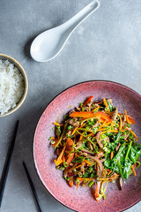 Top view salad with vegetables, meat and spinach. Pan-asian style salad. Bowl with healthy food flat lay. Copy space for design. Warm salad served with chopsticks and rice. appetizer