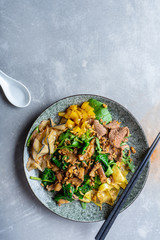 Top view pan-asian thai salad bowl. Flat lay food on grey stone background. Warm salad with veal, spinach, mushrooms and spices. Copy space. Banner, menu, poster photo