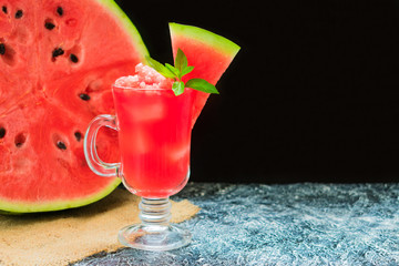  A refreshing watermelon smoothie in a glass decorated with mint leaves on a black background. Copy space