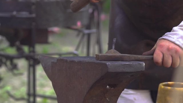 Blacksmith bending nail via hammering. Slavic and old culture days in Sobotka, Poland.  Slow motion.