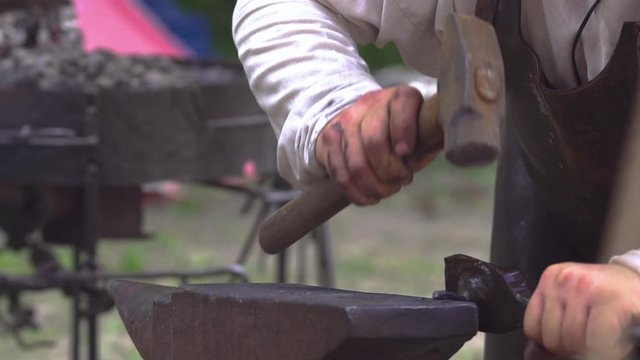 Blacksmith at work in outdoor smithy during Slavic and old culture days in Sobotka, Poland. Slow motion.