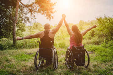 Handicapped couple resting in the forest near lake. Wheelchairs in the forest on the natural...