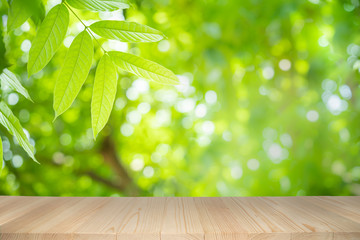 Empty wooden table on green nature background with beauty bokeh under sunlight.