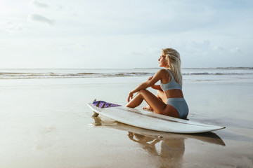 Surf girl with long hair go to surfing. Young surfer woman holding blank white short surfboard on a...