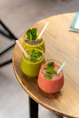 Row of healthy summer smoothies with berries, fruits and juices on a wooden table in the cafe