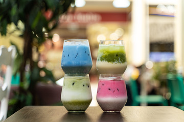 Four kinds of japanese matcha iced tea: pink, green and blue on blurred cafe background