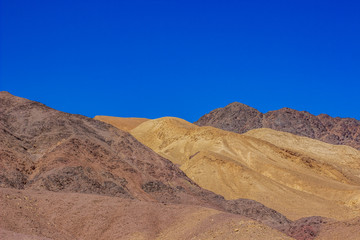 colorful desert sand stone hills dry scenic landscape photography of wilderness and dangerous natural environment, blue sky background 