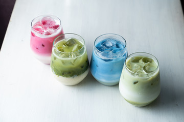 Top view of multi colored japanese matcha ice tea on a white table: green, pink and blue beverages