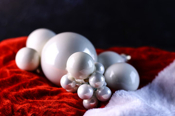 White Christmas tree toys on red and white fabric background. Different sizes pearl balls. Christmas and New Year background concept. 