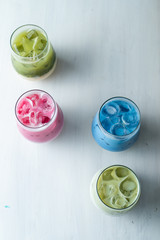 Top view of multi colored japanese matcha ice tea on a white table: green, pink and blue beverages