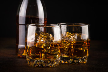 Whiskey in the glasses on dark background.