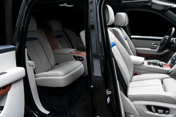 Modern luxury car white leather interior with natural wood panel. Part of leather car seat details...